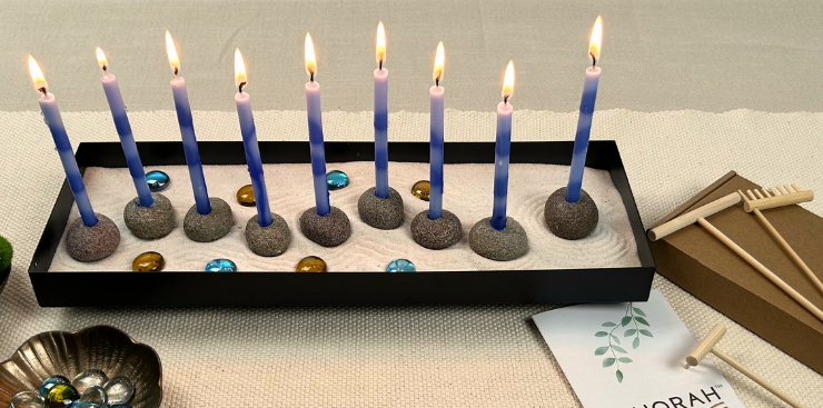 Menorah with lit candles on a wooden surface, featuring the brand 'Zenorah'.