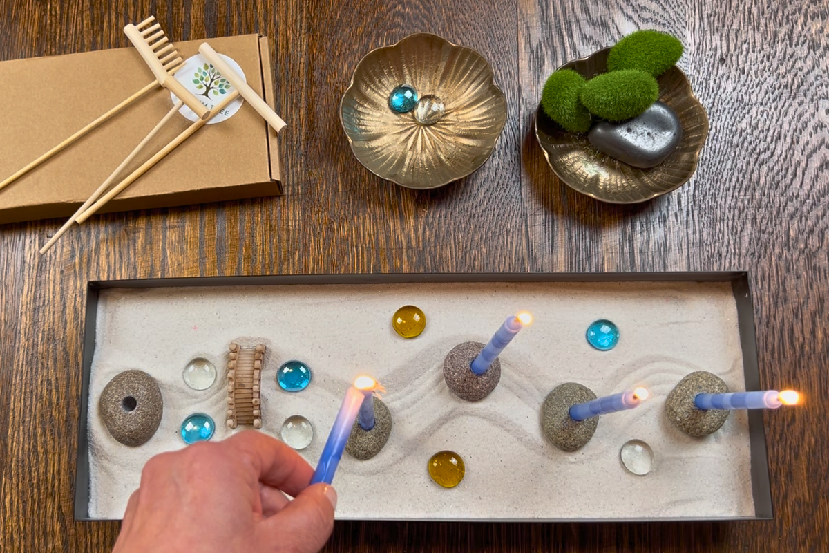 A hand lighting the candles in the rectangular Zenorah