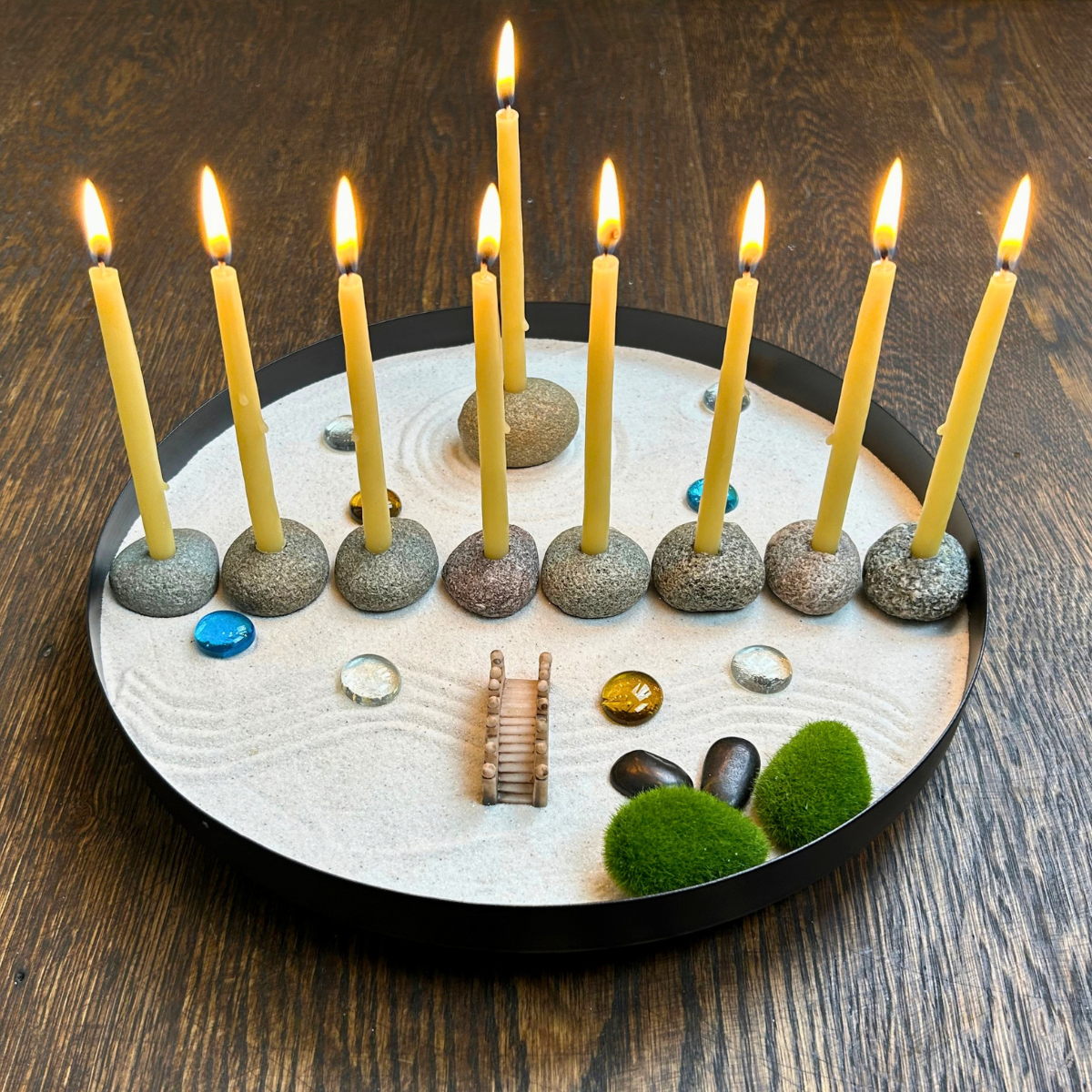 The round Zenorah lit with eight beeswax candles and the raised shamash