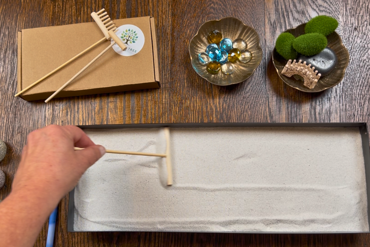 Smoothing the sand in the rectangular Zenorah tray with the bamboo smoother